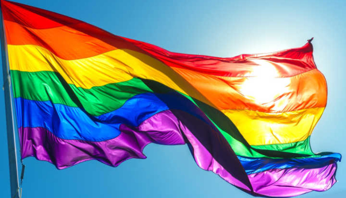 Rainbow flag on the blue sky background
